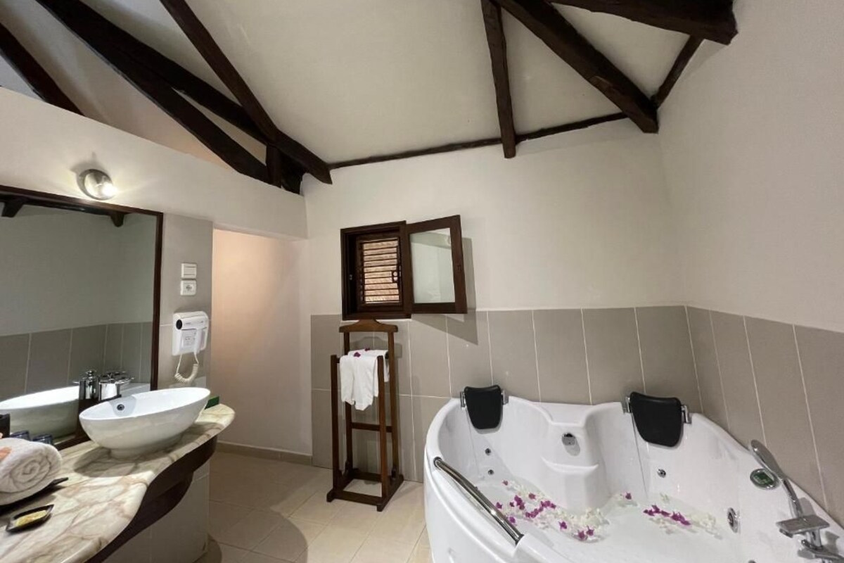 A bathroom with a large sink, a bathtub, and a mirror.