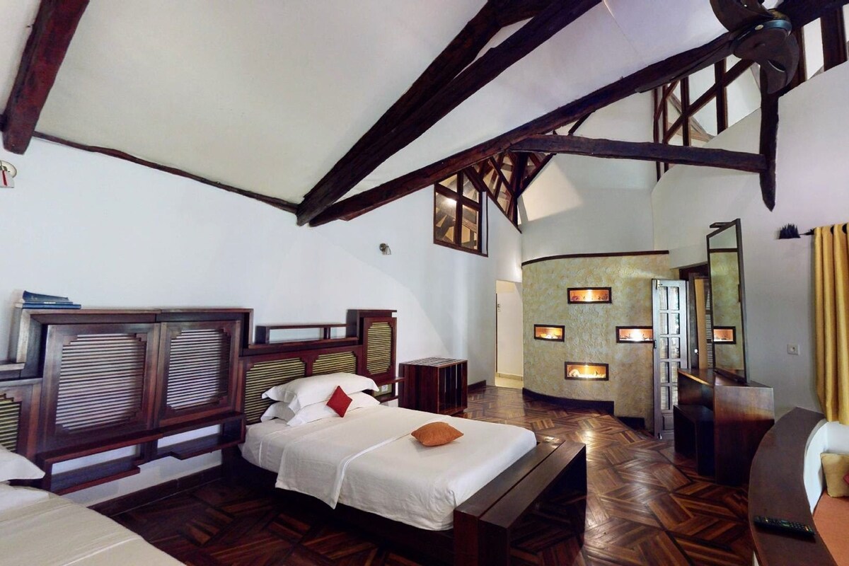 A spacious bedroom with a large bed, wooden headboard, and a built-in fireplace.
