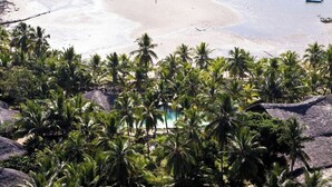 A beach with palm trees and a clear view of the ocean. - Ravintsara Wellness Hotel (Nosy Be)