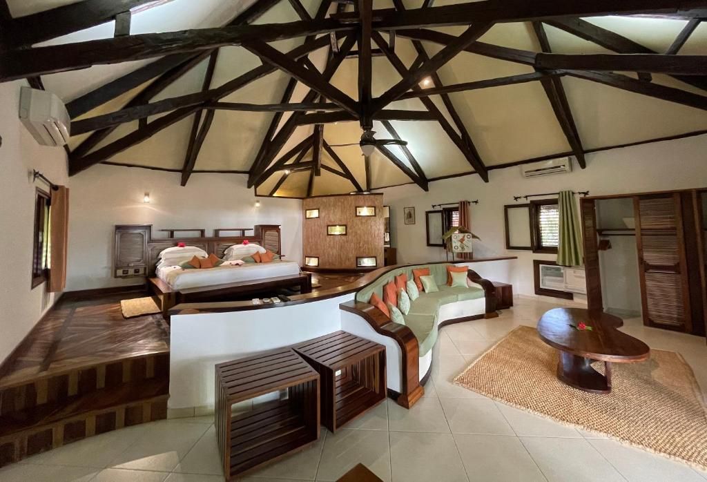 A spacious room with a high ceiling, a bed, a sofa, and a small table.