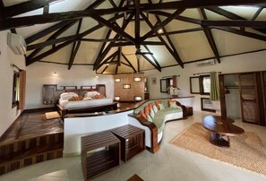 A spacious room with a high ceiling, a bed, a sofa, and a small table. - Ravintsara Wellness Hotel (Nosy Be)