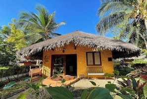 A small, single-story building with a thatched roof, surrounded by lush greenery and palm trees. - Ravintsara Wellness Hotel (Nosy Be)