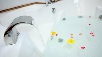 A bathtub with a chrome faucet and floral decorations in the water.