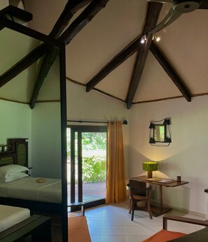 A room with a bed, a desk, a chair, and a window with curtains. - Ravintsara Wellness Hotel (Nosy Be)