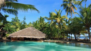 A clear pool with a thatched-roof hut, surrounded by palm trees and a beach. - Ravintsara Wellness Hotel (Nosy Be)