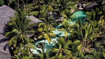 Een tropisch resort met meerdere zwembaden, omringd door palmbomen.