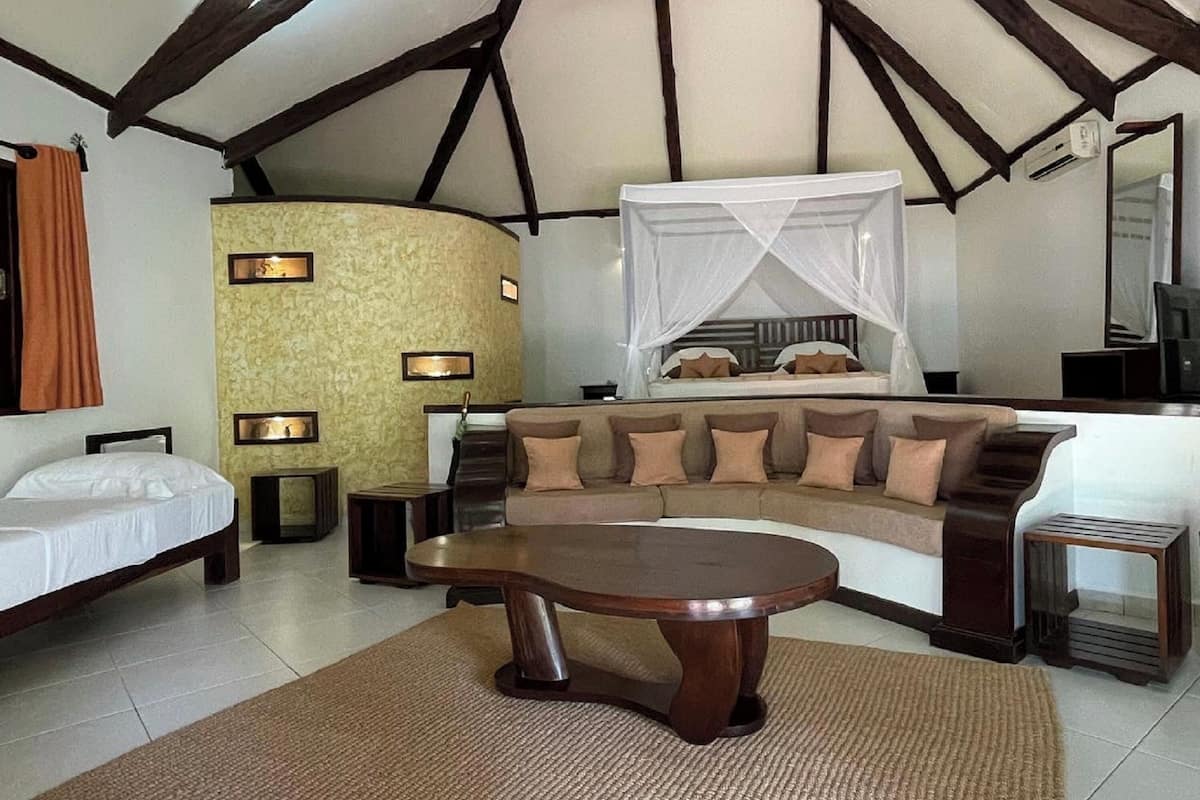 A room with a bed, a sofa, a coffee table, and a TV.
