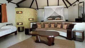 A room with a bed, a sofa, a coffee table, and a TV. - Ravintsara Wellness Hotel (Nosy Be)