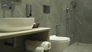 A modern bathroom with a large white sink, a toilet, and a shower area. - Tr Hotels (Ambala)