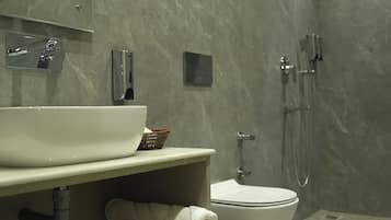 A modern bathroom with a large white sink, a toilet, and a shower area.