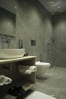 A modern bathroom with a large white sink, a toilet, and a shower area.