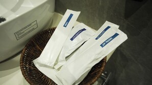A wicker basket containing three white packages labeled "Delma Kit" on a bathroom counter. - Tr Hotels (Ambala)