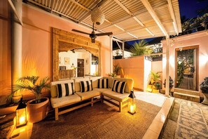 Un espace extérieur accueillant avec un canapé, des plantes en pot et une lanterne.
