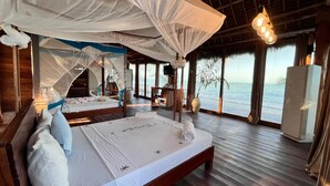 A room with a bed, a TV, and a view of the ocean. - Tiki Beach Club & Resort (Paje)