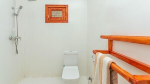 A small, compact bathroom with a shower, toilet, and a wooden-framed picture on the wall. - Tiki Beach Club & Resort (Paje)