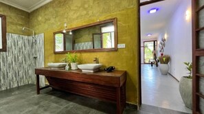 A bathroom with a wooden vanity, two sinks, a large mirror, and a shower area. - Tiki Beach Club & Resort (Paje)