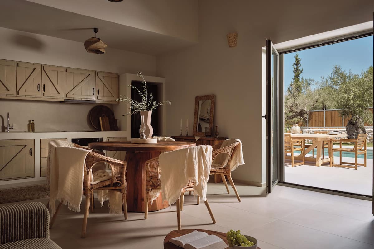 Une cuisine spacieuse avec des meubles de rangement en bois, une table à manger avec des chaises et une vue sur l’extérieur.