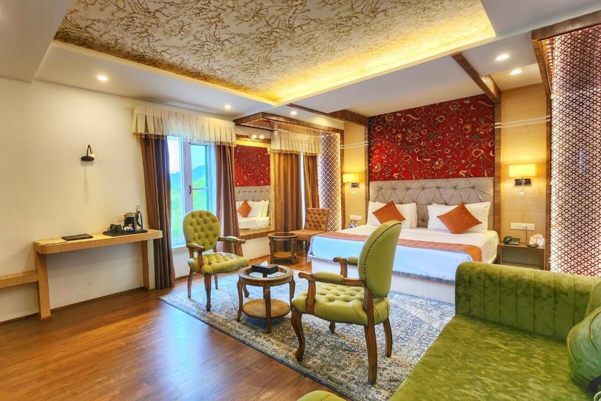 A hotel room with a large bed, two armchairs, a desk, and a sofa.