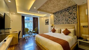 A hotel room with a large bed, a desk with a chair, a TV, and a window with curtains. - The Walnut Creek Hotel (Anantnag)