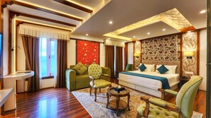 A hotel room with a bed, a sofa, a chair, a small table, and a window. - The Walnut Creek Hotel (Anantnag)