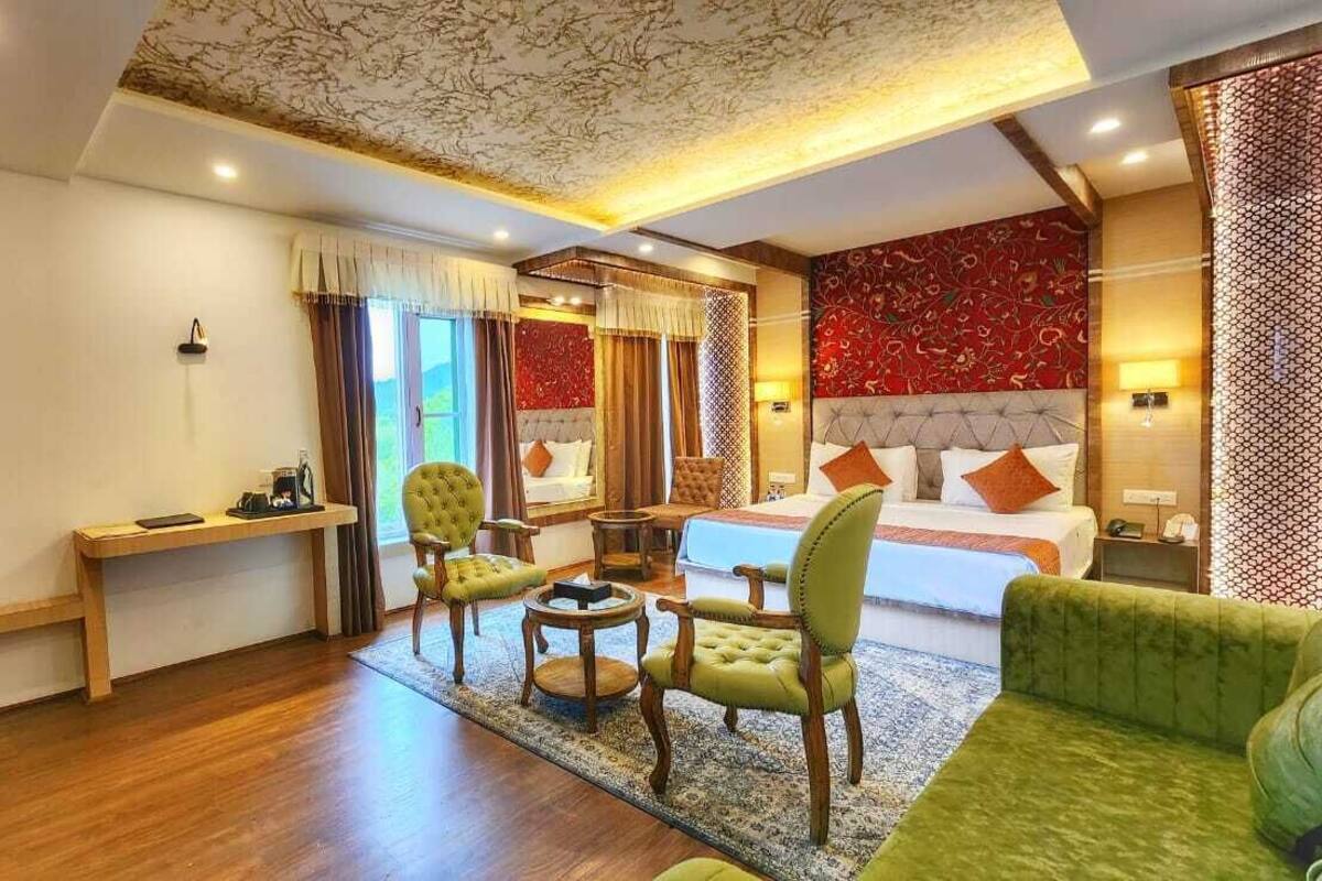 A hotel room with a large bed, two armchairs, a desk, and a sofa.