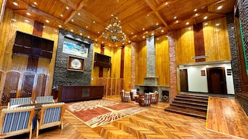 Un vestíbulo amplio con piso de madera en patrón de espiga, chimenea, candelabro y pared de acento de piedra.
