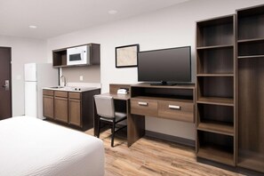Habitación de hotel con cama, escritorio con computadora, microondas, televisor y armario.