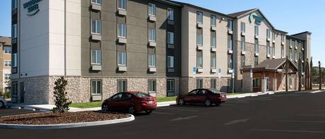 A multi-story hotel with a stone facade, multiple windows, and a parking lot with cars.