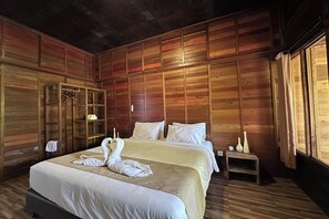 Una habitación con paneles de madera, una cama, una mesita de noche, un espejo y una ventana.
