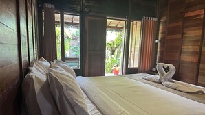Una habitación con cama, ventana con cortinas y vista a zonas verdes.