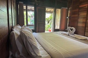 Una habitación con cama, ventana con cortinas y vista a zonas verdes.