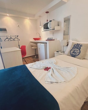Een hotelkamer met een bed, een bureau, een stoel, een magnetron en een kleine koelkast.
