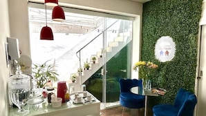 A modern kitchen with a glass island, red pendant lights, and a green wall.