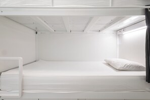 A bunk bed with a white mattress and a single pillow.