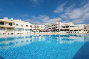 A swimming pool with modern buildings in the background. - Dunas Hostel & Guesthouse (Portimão)