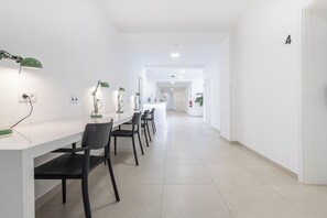 A modern, well-lit hallway with a long table and chairs, white walls, and a clean, minimalist design. - Dunas Hostel & Guesthouse (Portimão)