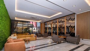 A modern lobby with a green wall, seating area, and a wine rack.