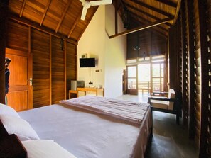 A bedroom with a large bed, wooden walls, a ceiling fan, a TV, and a view of the outdoors. - La Seran Eco Resort - Ella (Bandarawela)