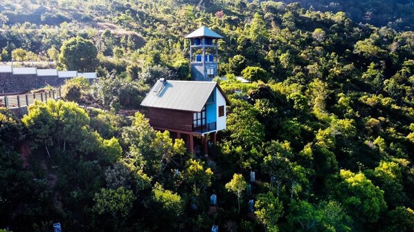 A wooden cabin with a blue roof and a tower, surrounded by dense forest. - La Seran Eco Resort - Ella (Bandarawela)