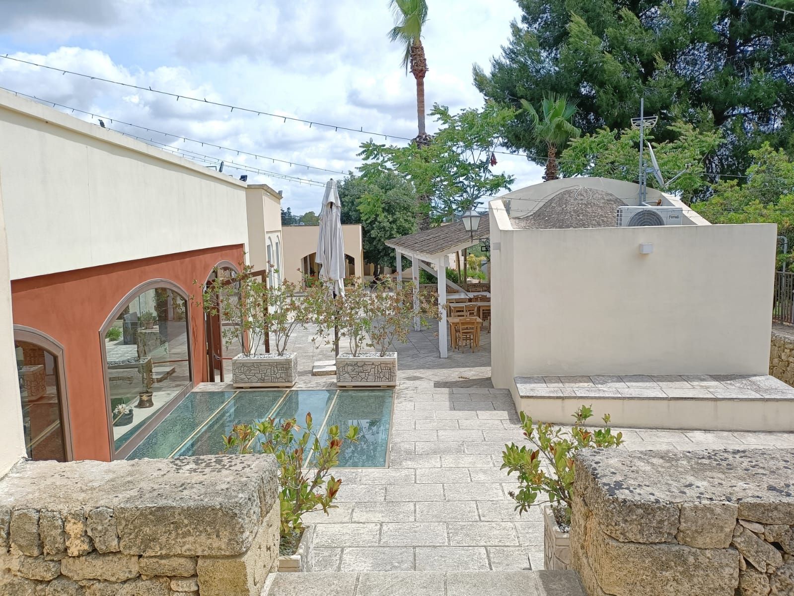 Une cour avec une piscine, des murs en pierre et des espaces de détente en plein air.