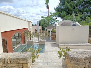 Une cour avec une piscine, des murs en pierre et des espaces de détente en plein air.