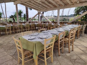 An outdoor dining area with tables set for a meal, surrounded by stone walls and greenery. - Il Trappeto (Gallipoli)