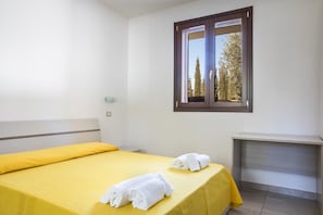 A hotel room with a bed, a nightstand, and a window with a view of trees. - Il Trappeto (Gallipoli)