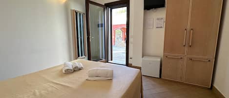 Un dormitorio con cama, armario, un calentador pequeño y una puerta que da al exterior.