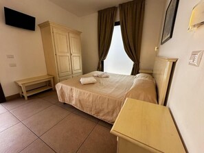 A bedroom with a bed, a wooden bench, a wardrobe, and a bedside table. - Il Trappeto (Gallipoli)