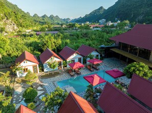 Een resort met meerdere villa's, een zwembad en weelderige begroeiing.