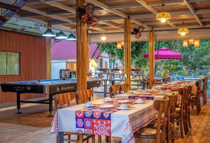 Een pooltafel, eettafels en stoelen in een restaurant met uitzicht op het landschap.