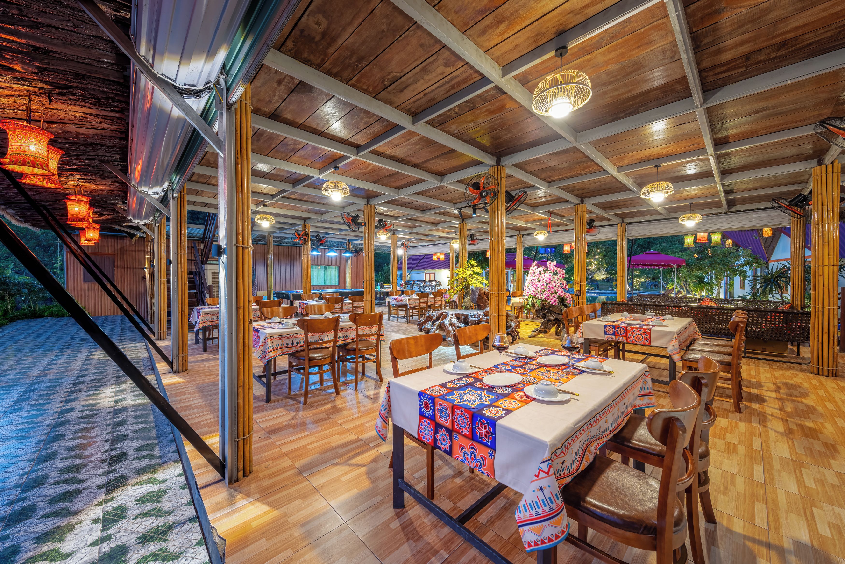 Un restaurant spacieux doté d’un plancher en bois et de tables dressées pour le service, offrant une vue sur l’extérieur.