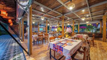 Un restaurante espacioso con suelo de madera y mesas dispuestas para comer, que ofrece vistas al exterior.