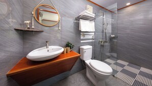 Une salle de bain moderne avec un meuble-lavabo en bois, un miroir rond, des toilettes et une douche à parois de verre.